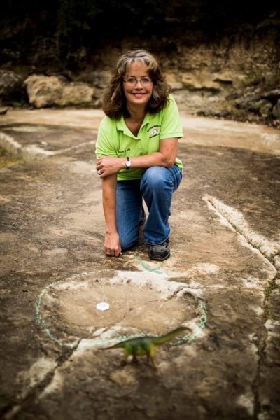 woman kneeling near dino foot print